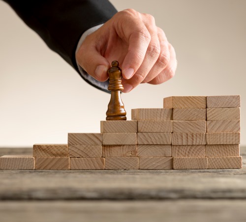 Person placing chess piece on a stack of blocks signifying the basics of disaster recovery planning.